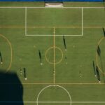 Aerial view of a soccer match on a green field in Alba, showcasing players and shadows.