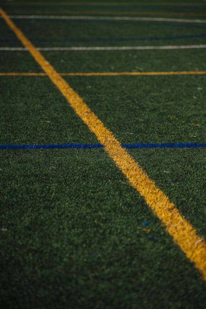 Close-up of artificial turf on a soccer field with a yellow line marking.